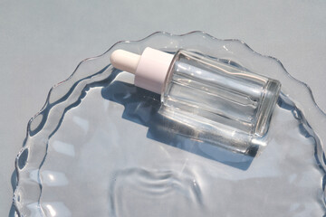 A bottle of serum in water on a blue background.