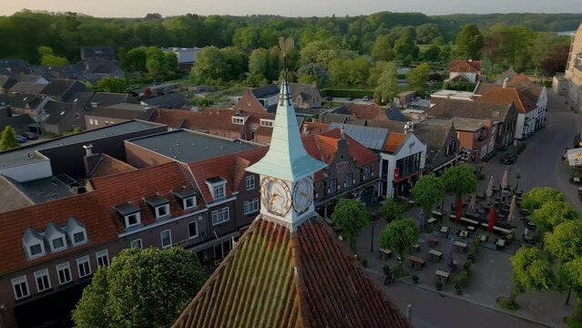 Drone circling around former Hall town clock tower of Dutch village Arcen and its neighbourhood at the shore of river Maas, Limburg, Netherlands