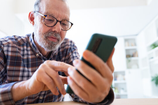 Mature adult caucasian man using mobile phone at home office.