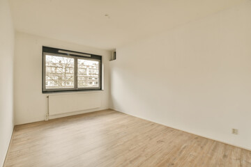 an empty room with wood floors and white walls, there is a large window in the wall to the right