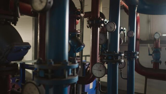Metal pipelines with pressure meters on flanges distribute hot steam in boiler house closeup. Complicated system of heat producing in mechanical room