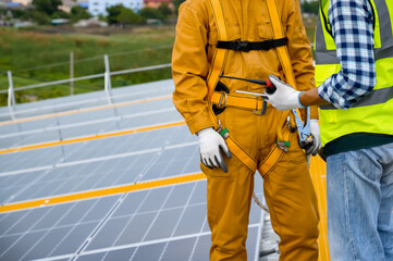 Close-up of Specialist technicians engineer holds a tablet and walkie-talkie for team contact and check to current power capacity of solar photovoltaic panels in the tablet.