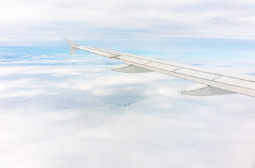 View from the airplane window at a beautiful cloudy sky and the airplane wing