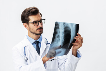 Male doctor in white coat and eyeglasses and stethoscope looking at patient X-rays for diagnosis on white isolated background, space for copy, space for text, health