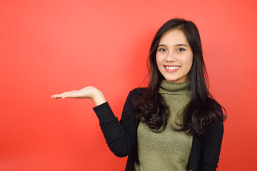 Showing and Presenting Product on Open Palm Of Beautiful Asian Woman Isolated On Red Background