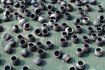Many pots of black clay are scattered on the bedding and dry in the sun. Handmade ceramic souvenirs...