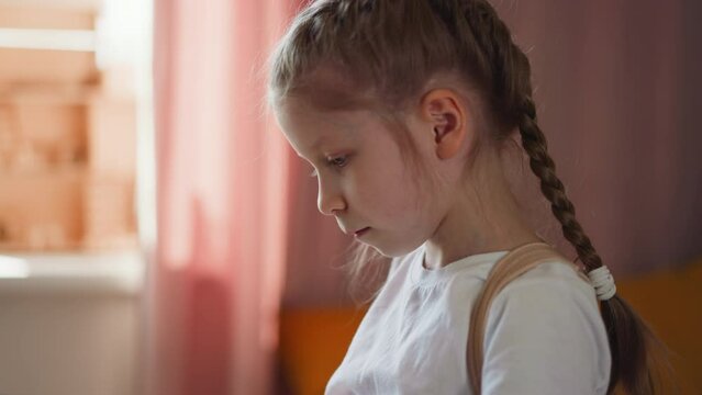 Attentive girl in white blouse and medical corset plays piano at home. Tranquil schoolgirl practices playing skills. Little female musician close side view on blurred background