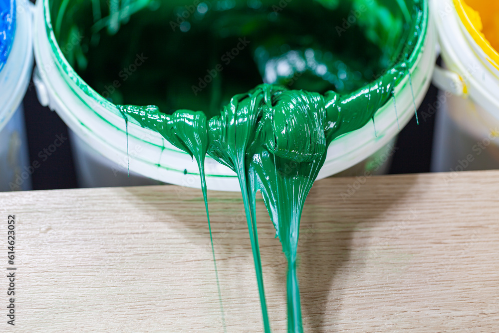 Poster .green paint dripping from white barrel..plastisol ink is used for printing on fabrics because it is