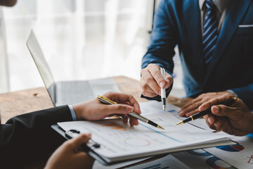 Young colleagues discuss business and analytical price charts using calculators and laptops to calculate financial, tax, accounting, statistics and analytical research ideas.