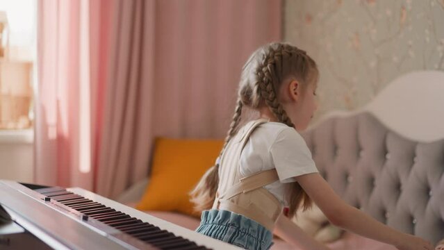 Girl catches little boy falling down near piano at home