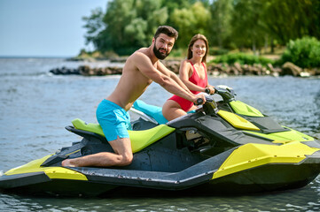 Beautiful couple sitting on jet ski enjoying honey moon at resort, spending active time.