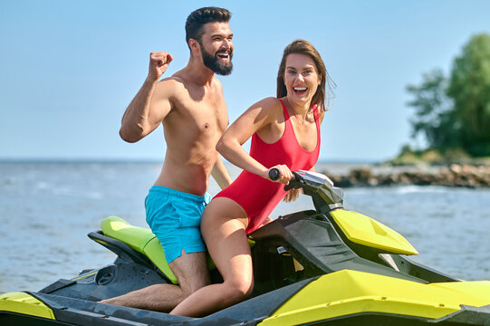 Beautiful couple sitting on jet ski enjoying honey moon at resort, spending active time.