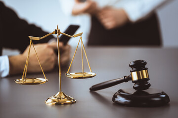 Focus shiny golden balanced scale on blurred background of lawyer working on desk at law firm...