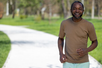 Mature african american man jogging in the park and looking contented