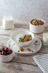 granola in a bowl with yogurt and fresh cherries