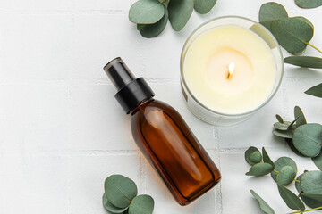Bottle of natural cosmetic oil, aroma candle and eucalyptus leaves - obrazy, fototapety, plakaty