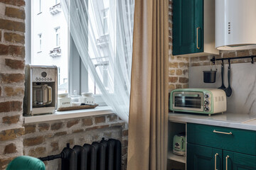 Modern retro-style kitchen with green cabinets and brick walls