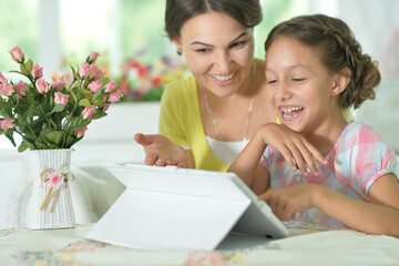 happy mother and daughter using tablet together at home