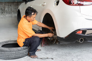 Fototapeta na wymiar Asia man mechanic checking brake disc at car service 