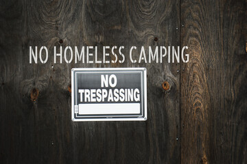 Urban no homeless camping sign on boarded up building