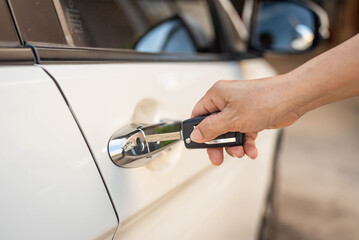 Female hand pushing remote key of white car