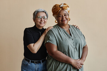 Waist up portrait of two senior women posing standing together and smiling at camera happily
