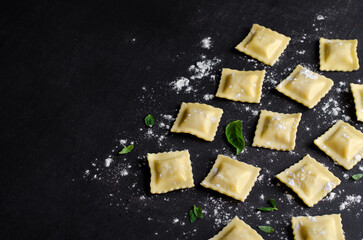 Raw Ravioli with Flour and Basil on Dark Background