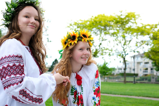 beautiful young women girls weaving wreaths walking laughing chatting in park in garden embroidered national ukrainian shirts wreaths of sunflower flowers and forest white flowers beautiful vyshyvanka