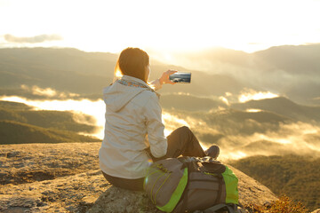 Trekker taking photo of a mountain on smartphone - obrazy, fototapety, plakaty