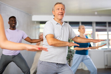 Emotional elderly man practicing hip-hop movements during adult group dance class in studio