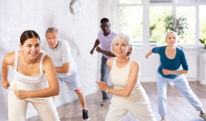 Active men and women of different ages practicing Hip-hop dance in training hall during dancing classes