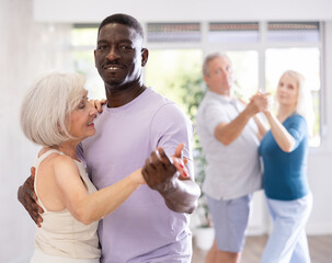African American man is enjoying his hobby of dancing salsa with his elderly partner at fitness class, relishing in movement and activity. It great way for them to stay active and have fun together.