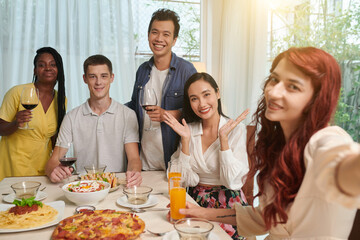 Young woman taking selfie with friends at dinner table