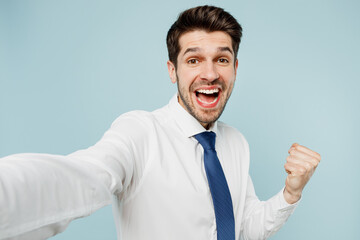 Close up young employee business man corporate lawyer wears classic formal shirt tie work in office do selfie shot pov on mobile cell phone do winner gesture isolated on plain blue background studio.
