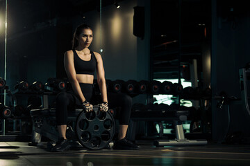 Fototapeta na wymiar Sporty woman doing exercises with heavy weights plates in gym.