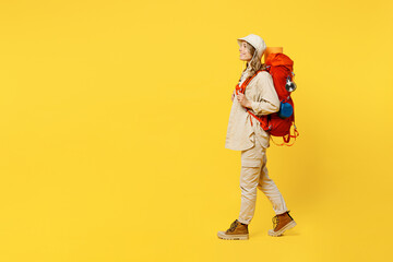 Full body side view young woman carrying bag with stuff mat walking going isolated on plain yellow background. Tourist leads active lifestyle walk on spare time. Hiking trek rest travel trip concept.