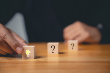 Creative consulting and innovative solutions. Hand holding wooden block with glowing light bulb icon. Business strategy suggestion for new initiative. Success through imagination and expertise.