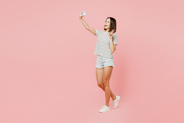 Fototapeta na wymiar Full body young caucasian woman she wears casual clothes t-shirt doing selfie shot on mobile cell phone post photo on social network isolated on plain pastel light pink background. Lifestyle concept.