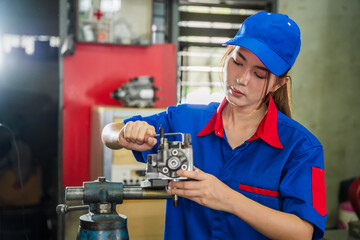 A female diesel engine mechanic in a blue uniform is working at the garage. Inspect and maintain...