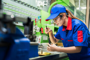 A female diesel engine mechanic in a blue uniform is working at the garage. Inspect and maintain...