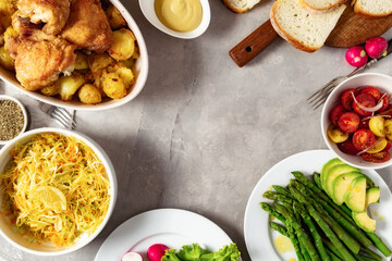 Home dinner table with healthy food. Frame from set of various food from baked new potatoes with chicken thighs, vegetables and salads on wooden table top view