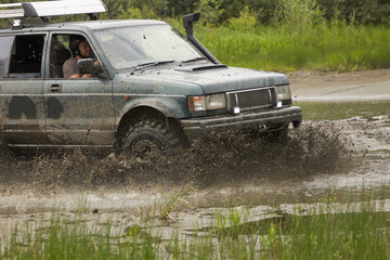 SUV or off-road vehicle crosses a river with splashes of dirty water. Extreme off-road tour in the...