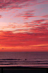 People swimming in the ocean under a red sunrise sky. Gold Coast, Australia.