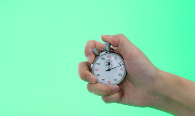 People hand holding stopwatch on green background
