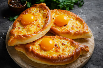 Ajarian Khachapuri, filled with cheese and topped with egg yolk, traditional Georgian Khachapuri on Dark Background