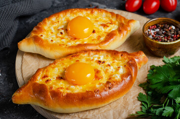 Ajarian Khachapuri, filled with cheese and topped with egg yolk, traditional Georgian Khachapuri on Dark Background