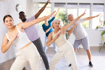 Active men and women of different ages practicing Hip-hop dance in training hall during dancing...