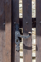 The black handle with a lock on a wooden gate