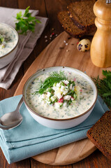 Cold Okroshka Soup with Eggs, Vegetables, Meat, Herbs and Kefir on a Wooden Background, Summer Soup