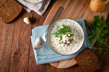 Cold Okroshka Soup with Eggs, Vegetables, Meat, Herbs and Kefir on a Wooden Background, Summer Soup